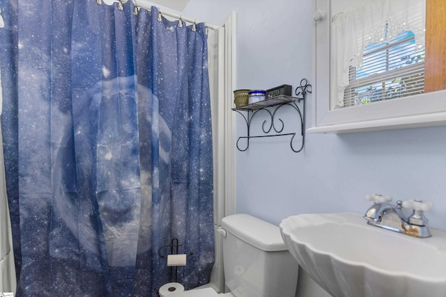 bathroom featuring toilet, sink, and curtained shower