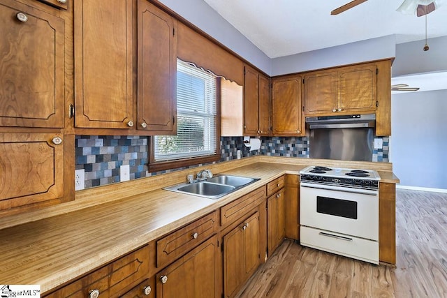 kitchen with light hardwood / wood-style floors, sink, white range, and tasteful backsplash