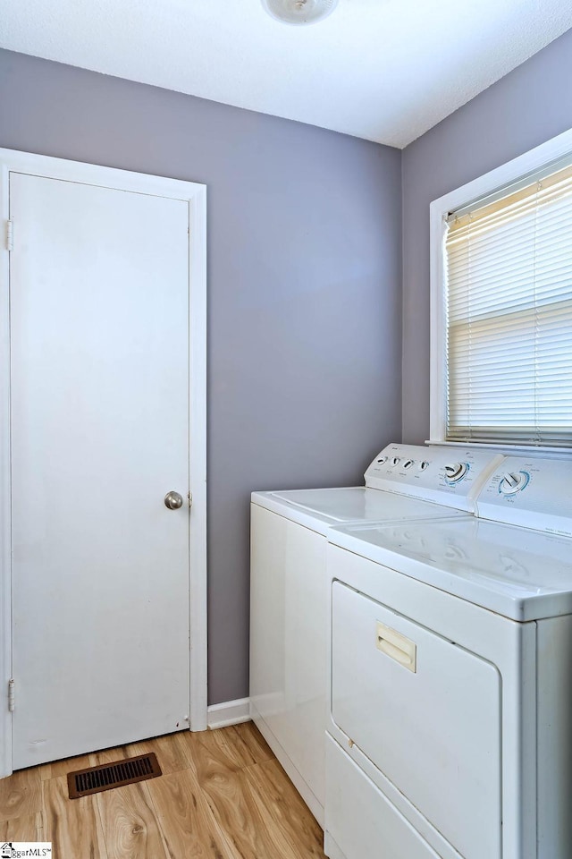 laundry room with separate washer and dryer and light hardwood / wood-style flooring