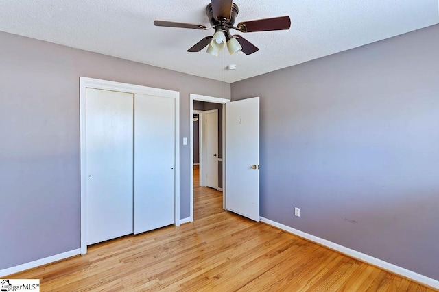 unfurnished bedroom with ceiling fan, a textured ceiling, a closet, and light hardwood / wood-style flooring