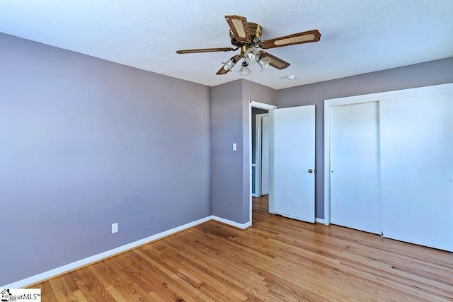 unfurnished bedroom featuring ceiling fan, a closet, a textured ceiling, and light hardwood / wood-style flooring