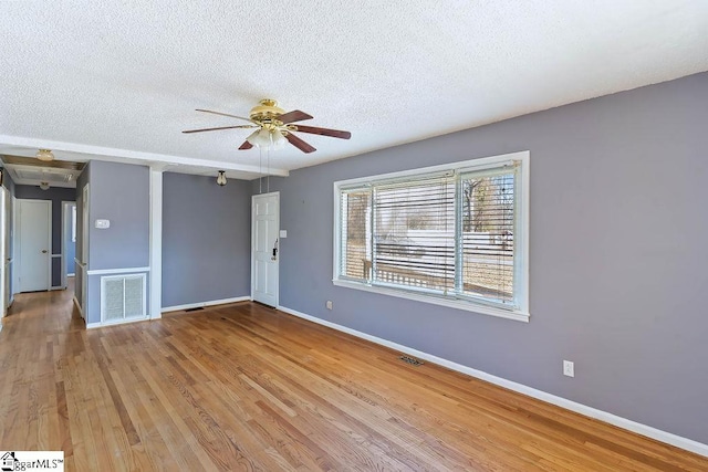 unfurnished room with ceiling fan, a textured ceiling, and light wood-type flooring