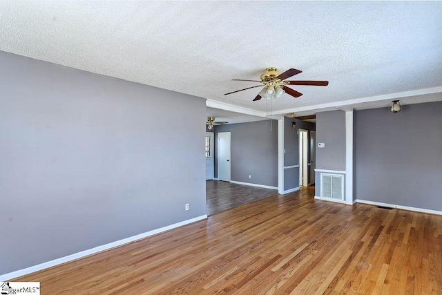 empty room with a textured ceiling, ceiling fan, and wood-type flooring