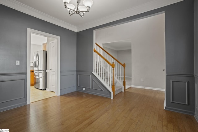 unfurnished room featuring crown molding, a chandelier, and light hardwood / wood-style flooring