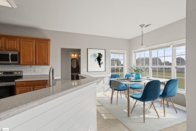 kitchen featuring backsplash, pendant lighting, appliances with stainless steel finishes, and a wealth of natural light