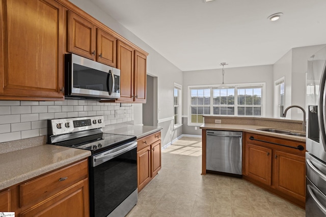 kitchen with decorative light fixtures, sink, backsplash, and appliances with stainless steel finishes