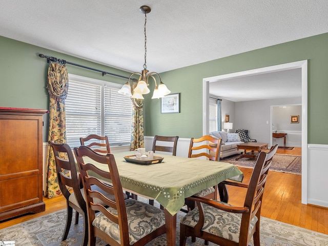 dining space featuring a textured ceiling, an inviting chandelier, and light hardwood / wood-style flooring