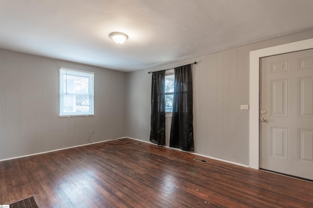 spare room with dark hardwood / wood-style floors and wooden walls