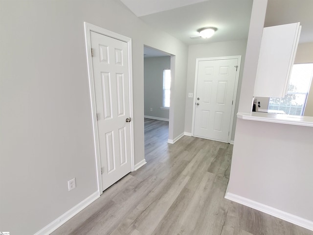 hallway featuring light wood-type flooring and plenty of natural light