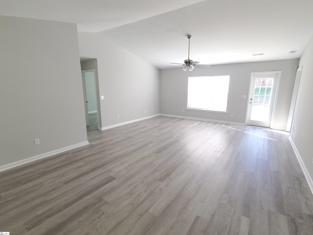 empty room with ceiling fan, vaulted ceiling, and light hardwood / wood-style flooring