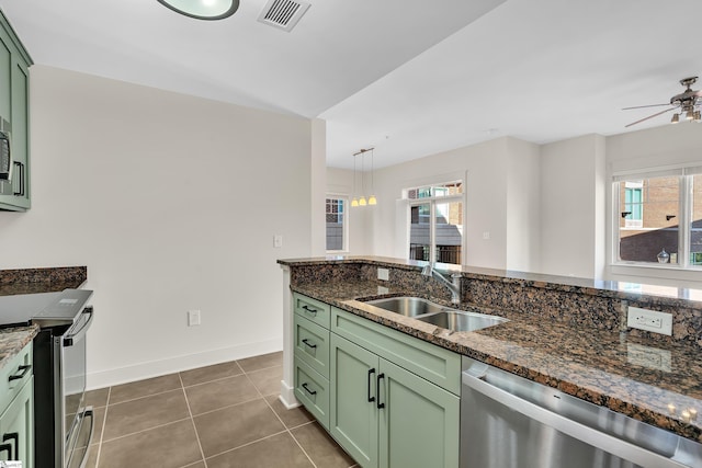 kitchen with stainless steel appliances, decorative light fixtures, sink, and dark stone countertops