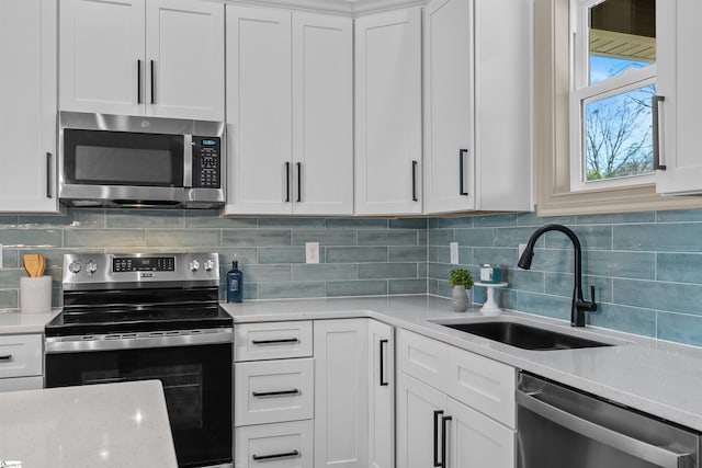 kitchen with sink, white cabinets, stainless steel appliances, and tasteful backsplash