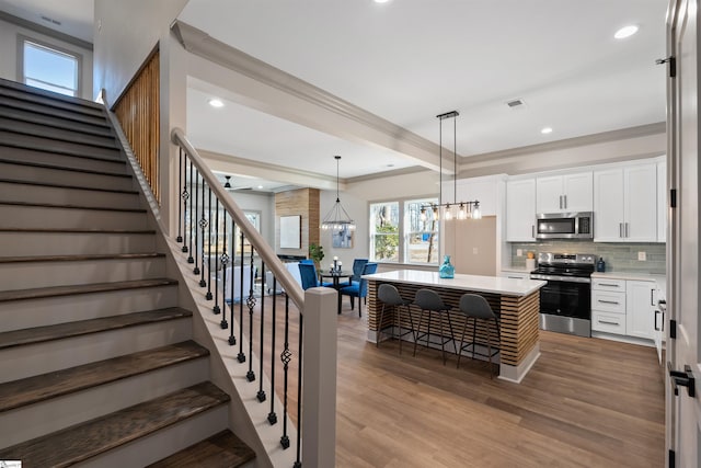 kitchen featuring stainless steel appliances, white cabinets, decorative light fixtures, and a center island