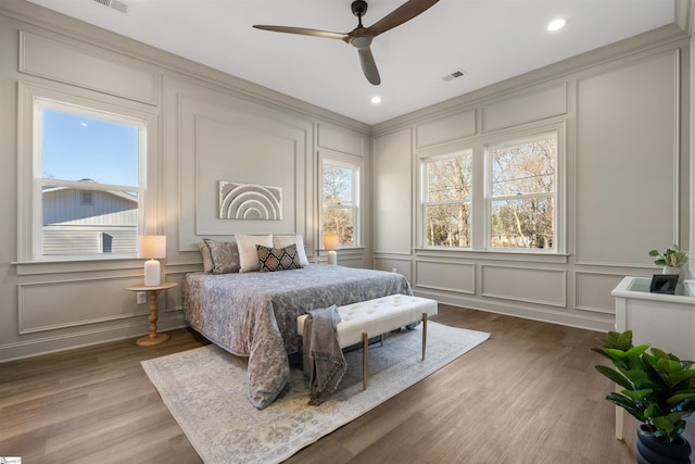 bedroom featuring ceiling fan, multiple windows, and hardwood / wood-style floors