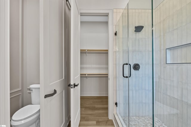 bathroom featuring an enclosed shower, toilet, and hardwood / wood-style floors