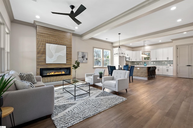 living room with ceiling fan, dark hardwood / wood-style flooring, beamed ceiling, and crown molding