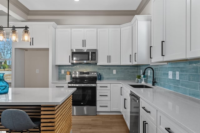 kitchen with white cabinetry, appliances with stainless steel finishes, backsplash, pendant lighting, and sink