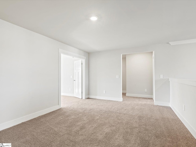 spare room with light carpet and baseboards