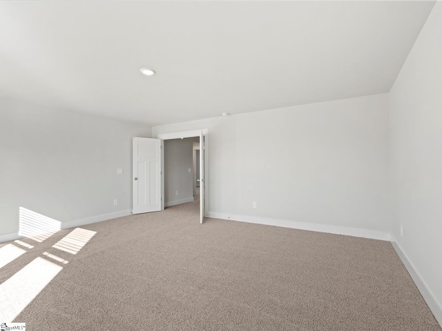 spare room with recessed lighting, light colored carpet, and baseboards