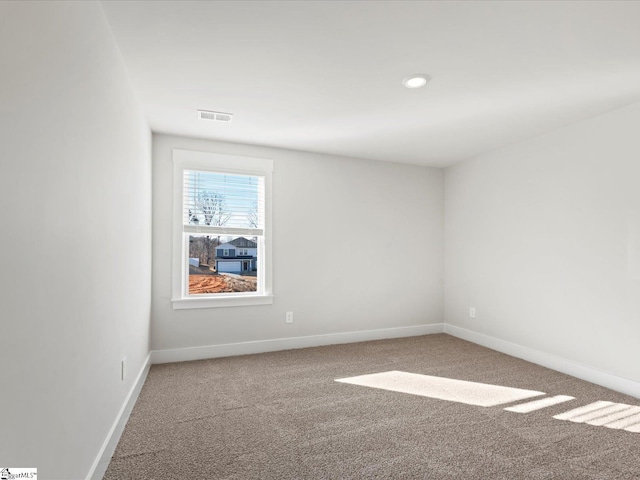 unfurnished room with carpet floors, visible vents, and baseboards