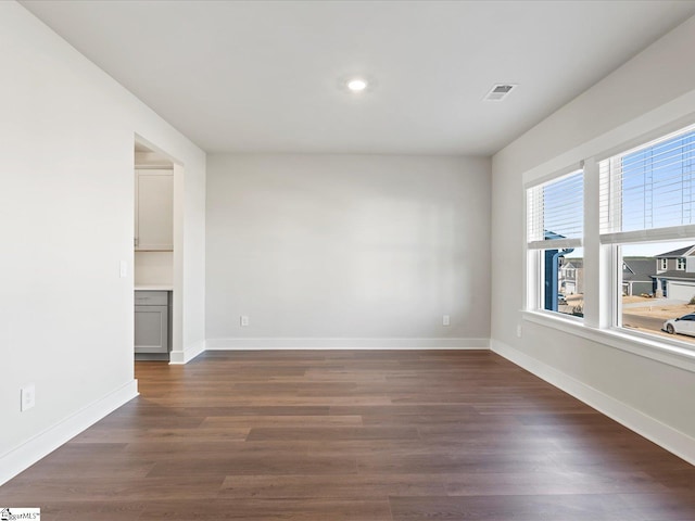 spare room with dark wood-style floors, baseboards, and visible vents