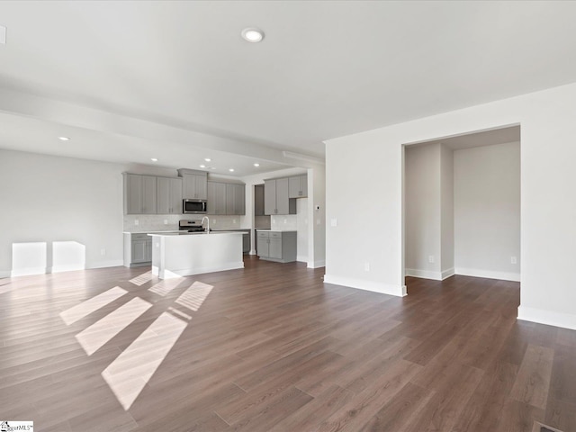 unfurnished living room featuring dark wood-style floors, baseboards, and recessed lighting