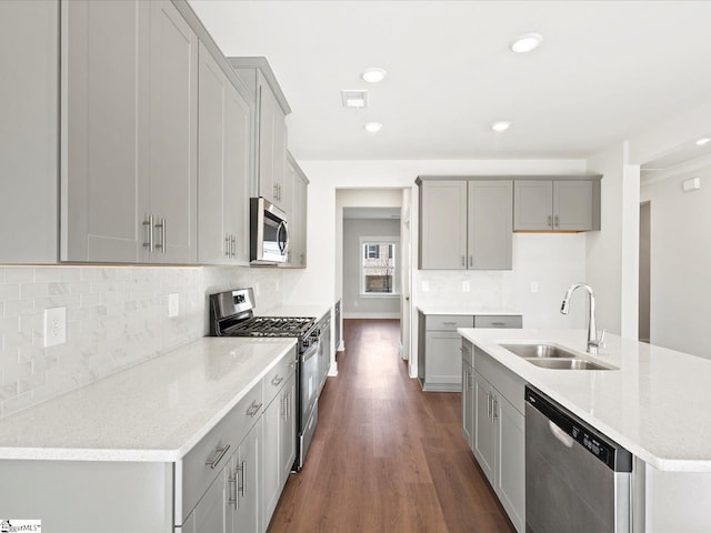 kitchen with stainless steel appliances, a sink, and gray cabinetry