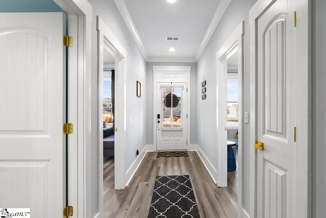 doorway featuring plenty of natural light, crown molding, and light hardwood / wood-style floors