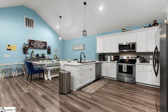 kitchen featuring kitchen peninsula, stainless steel appliances, tasteful backsplash, pendant lighting, and white cabinets