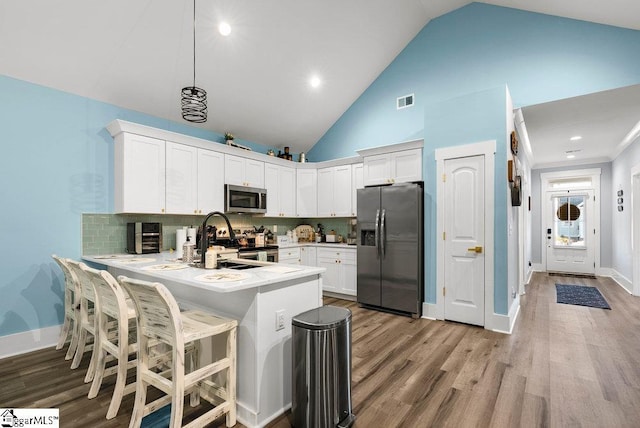 kitchen featuring kitchen peninsula, decorative backsplash, sink, appliances with stainless steel finishes, and white cabinets