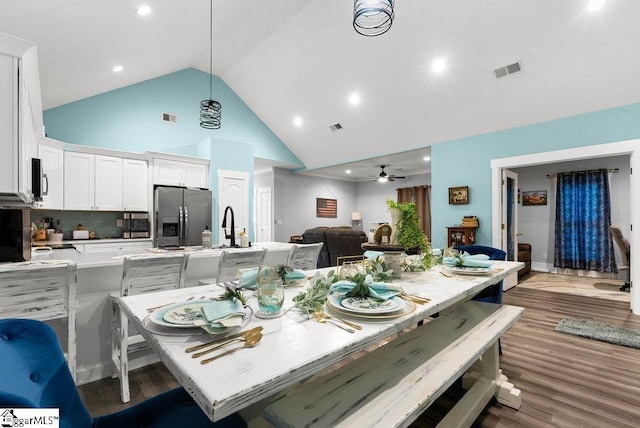 dining room with high vaulted ceiling, sink, wood-type flooring, and ceiling fan