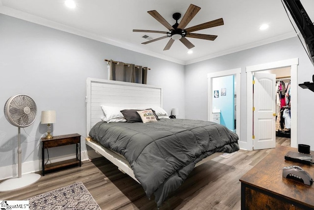 bedroom with a walk in closet, a closet, ceiling fan, light hardwood / wood-style flooring, and crown molding