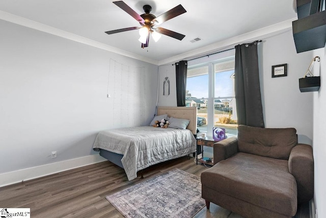 bedroom with ceiling fan, dark hardwood / wood-style floors, and ornamental molding