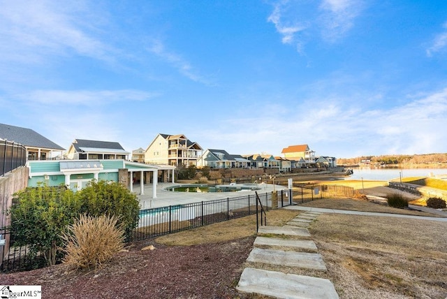 view of yard featuring a fenced in pool, a water view, and a patio