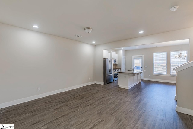 unfurnished living room featuring dark wood-type flooring, sink, and a notable chandelier