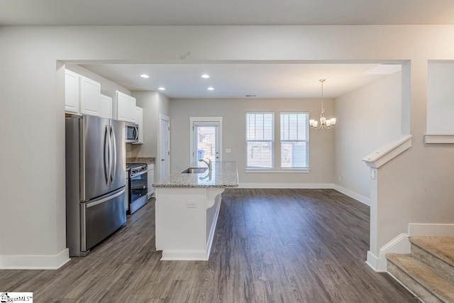 kitchen with white cabinetry, an island with sink, stainless steel appliances, decorative light fixtures, and sink