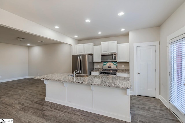 kitchen with appliances with stainless steel finishes, a kitchen island with sink, white cabinets, a breakfast bar, and sink