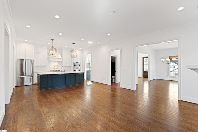 unfurnished living room featuring plenty of natural light, dark hardwood / wood-style floors, crown molding, and a chandelier