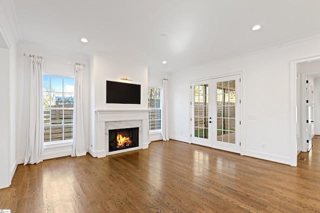 unfurnished living room with french doors, plenty of natural light, ornamental molding, and dark hardwood / wood-style floors