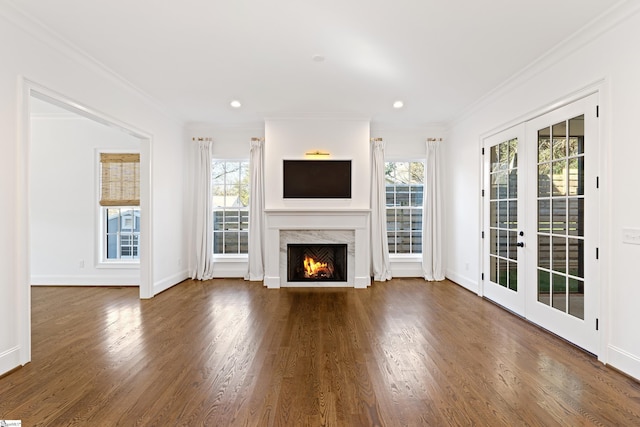 unfurnished living room featuring a wealth of natural light, a premium fireplace, crown molding, and french doors