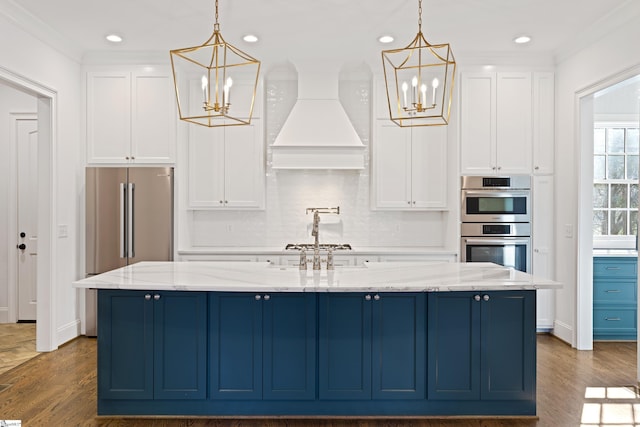 kitchen with light stone countertops, premium range hood, white cabinetry, and hanging light fixtures