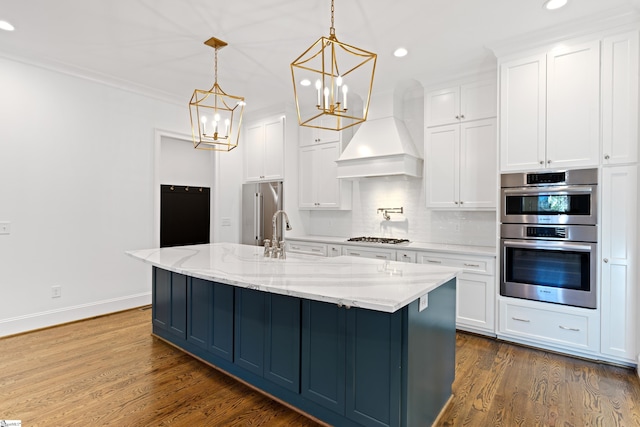 kitchen featuring premium range hood, appliances with stainless steel finishes, light stone countertops, pendant lighting, and white cabinets