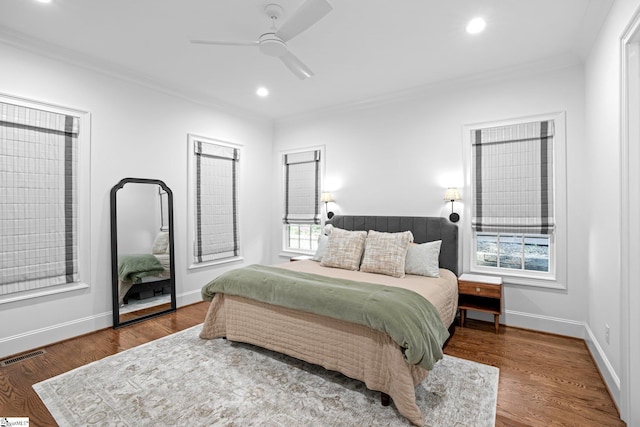 bedroom featuring ceiling fan, wood-type flooring, ornamental molding, and multiple windows