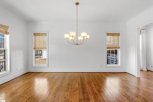 unfurnished dining area with hardwood / wood-style floors, ornamental molding, and a notable chandelier