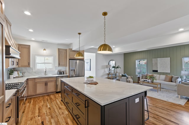 kitchen featuring pendant lighting, a center island, sink, light wood-type flooring, and appliances with stainless steel finishes