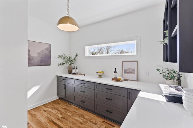 bar featuring light hardwood / wood-style floors, hanging light fixtures, and gray cabinets