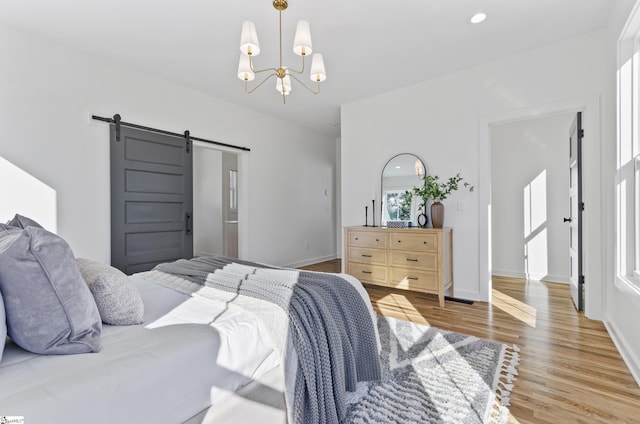 bedroom with wood-type flooring, a barn door, and an inviting chandelier