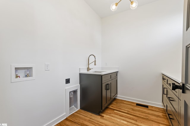 laundry area featuring washer hookup, cabinets, light hardwood / wood-style floors, and sink