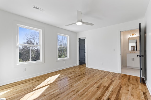 unfurnished bedroom featuring ensuite bath, ceiling fan, and light hardwood / wood-style floors
