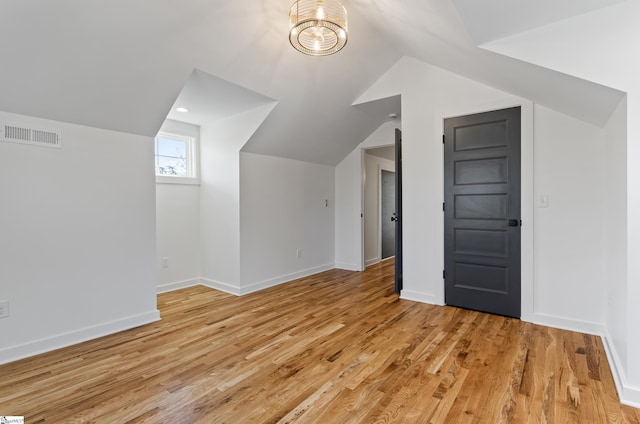 additional living space with vaulted ceiling and light hardwood / wood-style floors